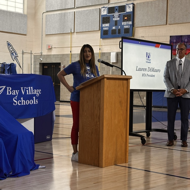 a female at the podium speaks to her colleagues