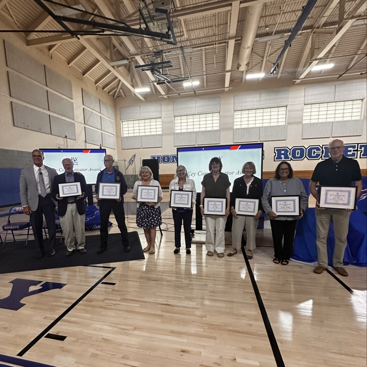 a group of senior citizens awarded by a school superintendent in a gym  