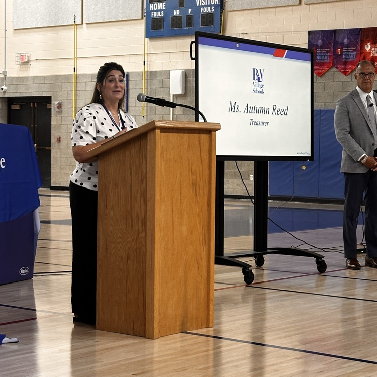 a woman at the podium speaking to colleagues 