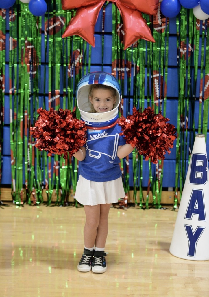 A photo of a young girl in a cheerleading costume learning a cheer.