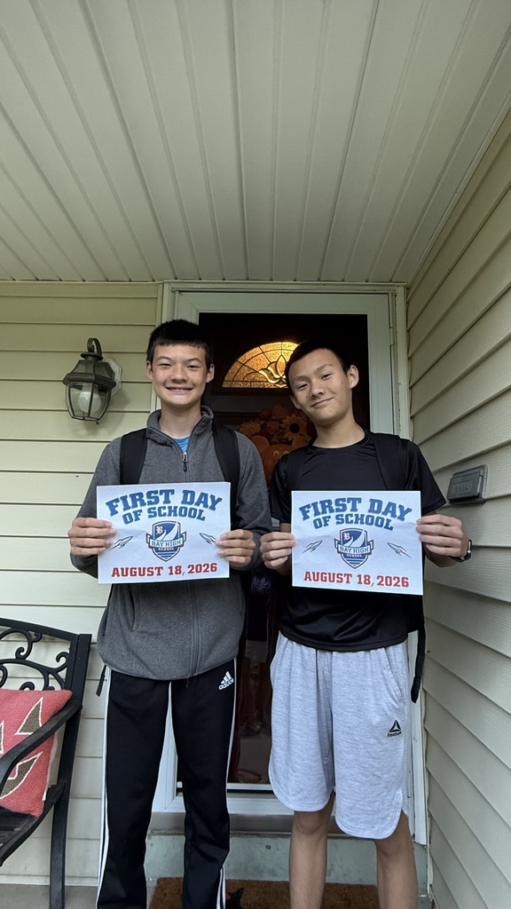 Two brothers standing on their front porch holding first day of high school signs.