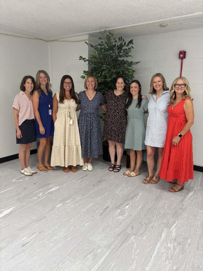 Eight first-grade teachers stand arm in arm, posing for a first day of school photo.