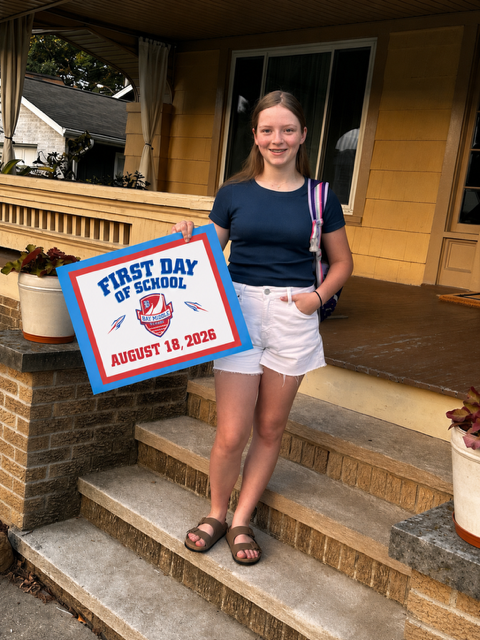 A middle school girl is standing on her front porch holding a first day of school sign.