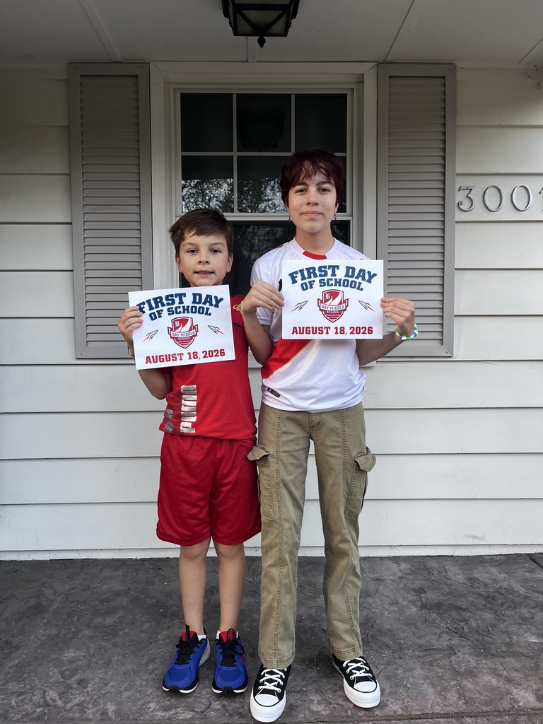 A brother and sister outside on the porch holding first day of school signs. They are in middle school.