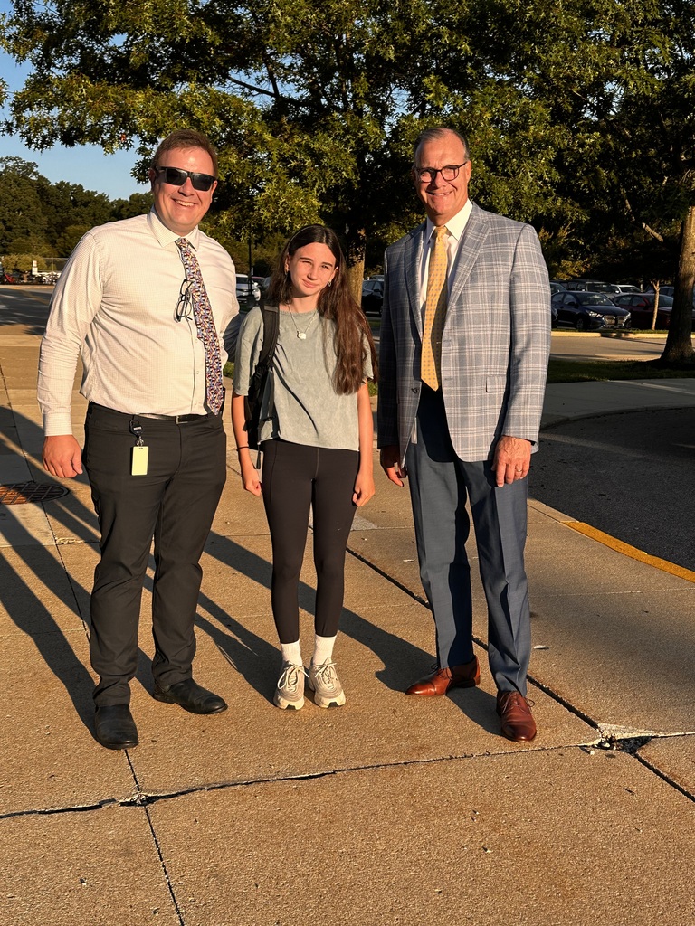 First day of school photo with a middle school student flanked by the assistant principal and the superintendent.