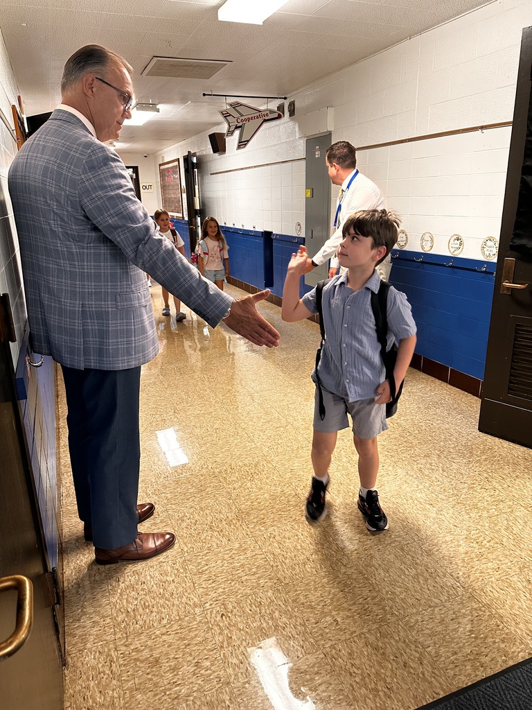 First day of school photo of an elementary boy in the hallway giving his superintendent a high-five. 
