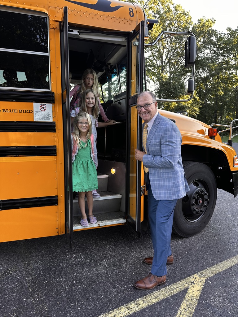 Elementary students get off the bus at school on their first day and are greeted by their superintendent.