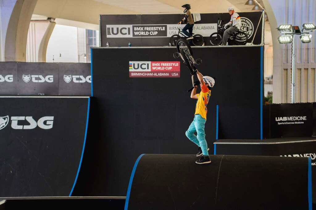 A BMX rider lifting his bike in the air while on a course.