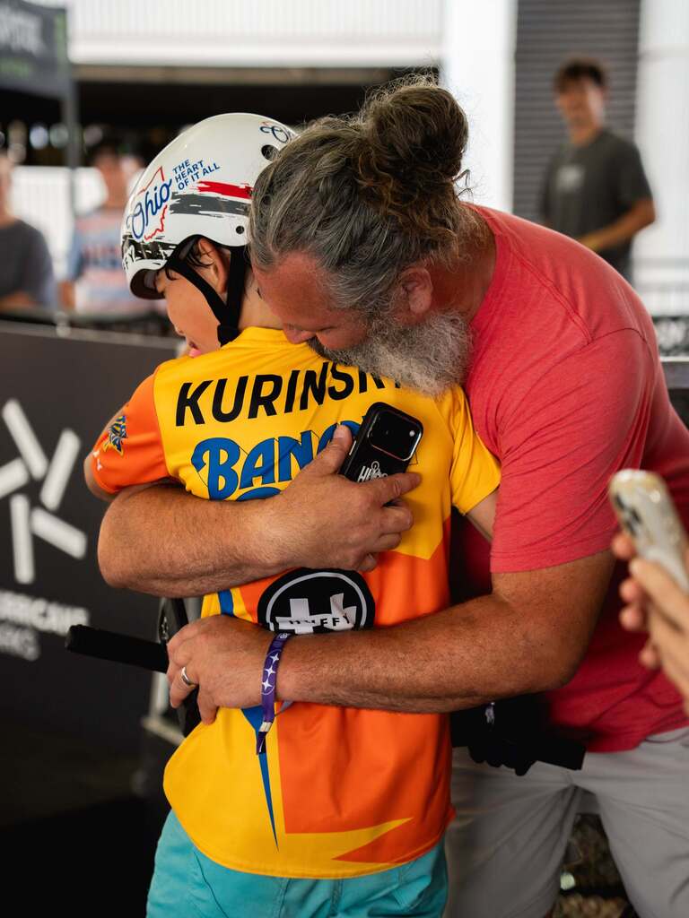 A young BMX rider gets a hug from his dad.