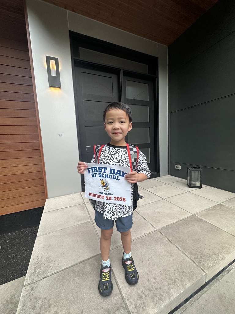 A boy standing on his front porch with a first day of Kindergarten sign.