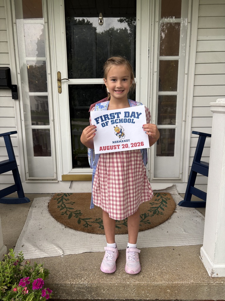 kindergarten student standing on her front porch holding a first day of school sign.