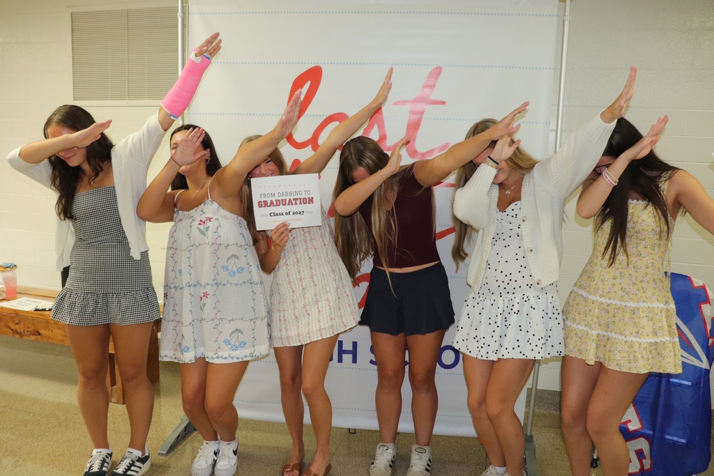 Senior girls dabbing in front of a first day of school sign.