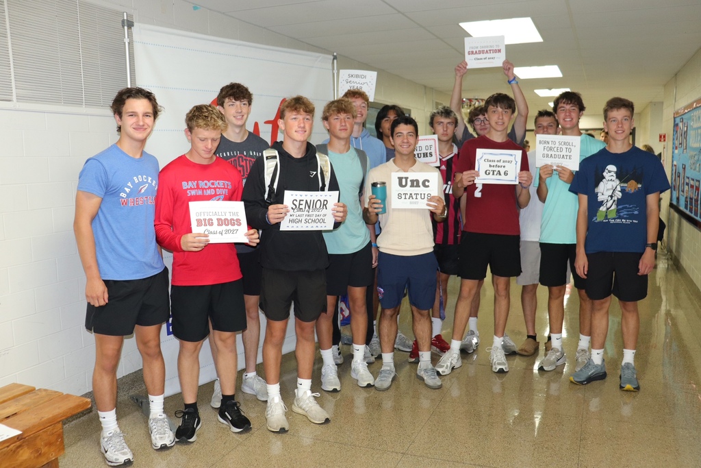 Senior boys holding signs in the hallway of their school on their last first day of school.