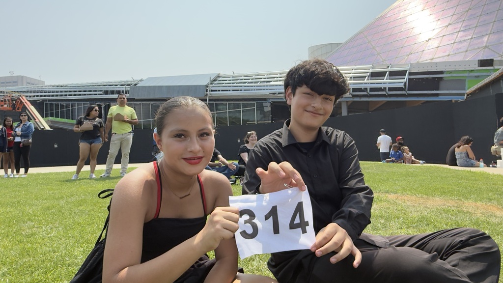 A middle school student and her salsa dancing partner holding up their dance number outside the Rock Hall.