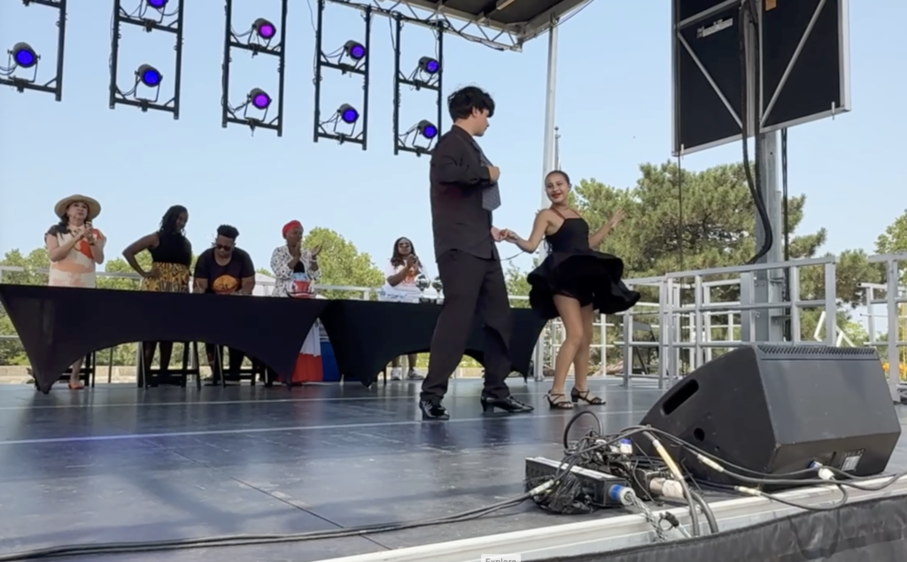 A student and her dance partner salsa dancing on a stage in downtown cleveland.