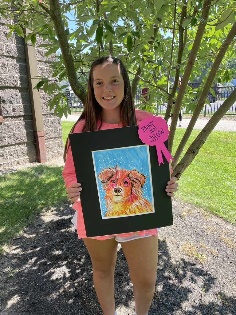 a middle school student holds her best in show artwork of a dog.