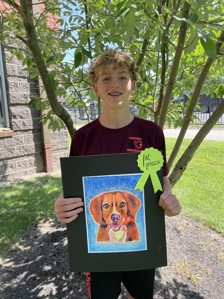 a middle school boy holds his first-place artwork of a dog.