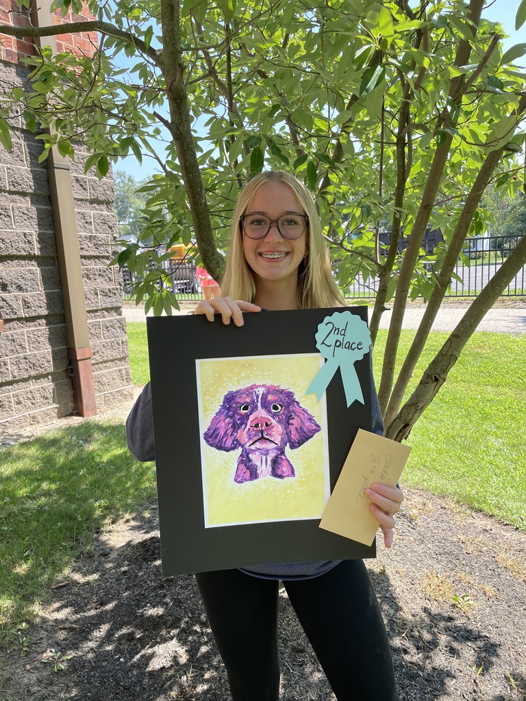a middle school student holds her 2nd place artwork of a dog painting.