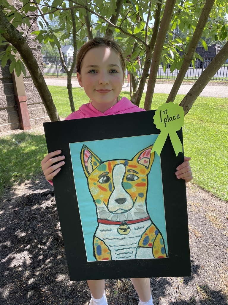 A middle school student holding a first-place piece of artwork that is a dog painting.