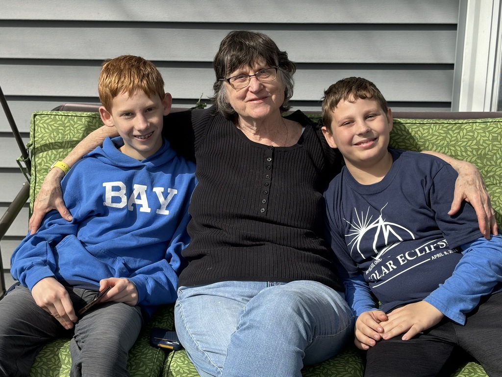 A Bay Village grandma flanked by her two grandsons, seated on a couch on the front porch.