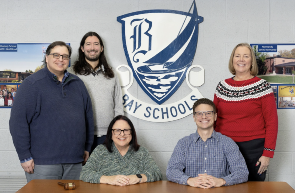 Board Group Photo for 2026, including five Board members standing and seated at a table with the district crest in the background.
