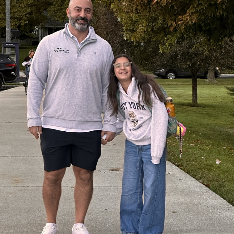 A man in his daughter, arriving at her school in the morning.