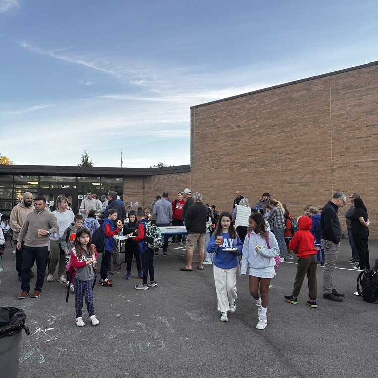 students and their parents outside at an event at their school near the playground area