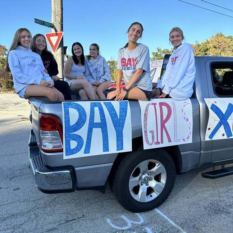 The Bay Girls Cross Country team is in the back of a silver pick up truck ready to ride in the homecoming parade.