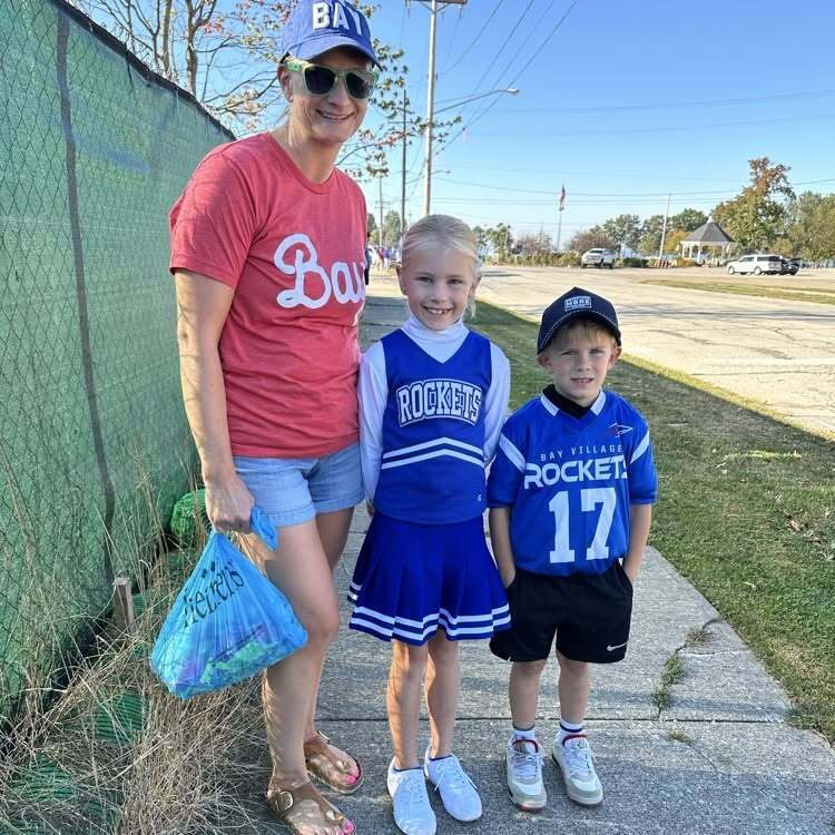 A family of three dressed in red, white and blue spirit wear pose with the candy they collected during the parade.