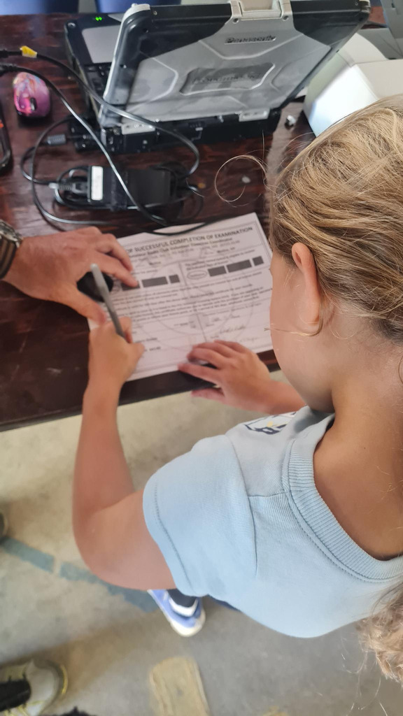 An elementary student signs her Ham Radio certificate paper.