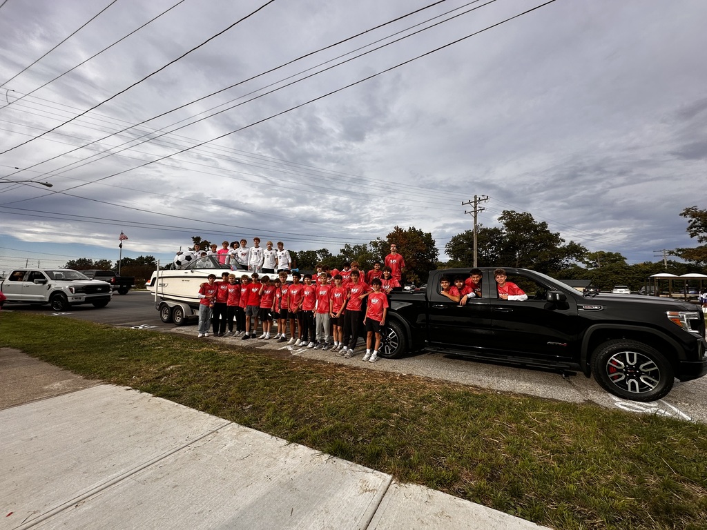 Boys soccer team standing by a pick up truck lining up for the homecoming parade. All in red shirts.
