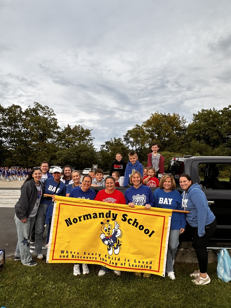 Teachers and students holding a yellow banner standing by a pickup truck.