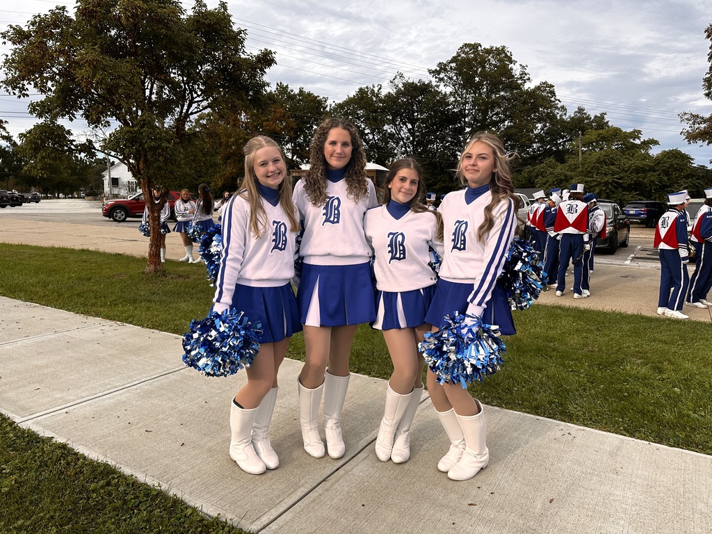 Four Rockette drill team members in blue and white uniforms with their poms.