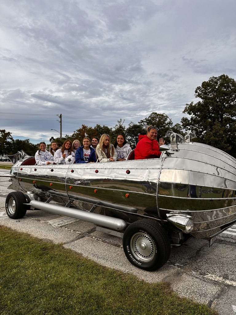 A silver rocket car with students on board waves as they line up for the homecoming parade.