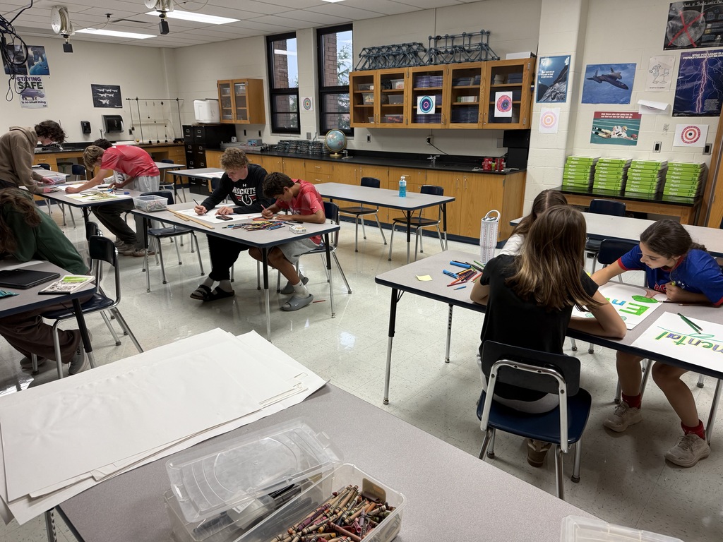 Students seated at tables making spirit posters.