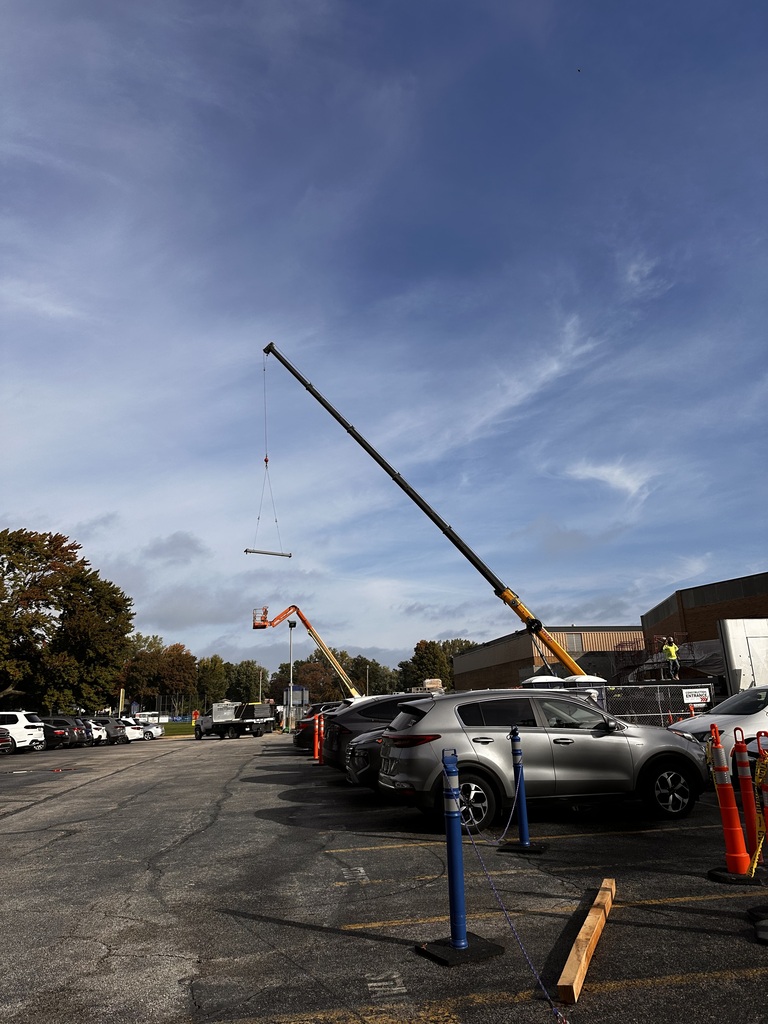 A crane carries a beam over to the construction site.