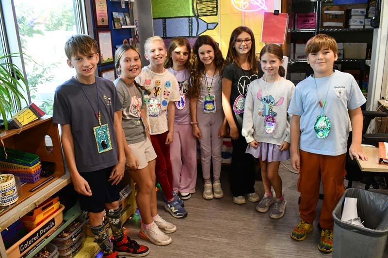 Group photo of students and teachers in brightly decorated classroom.