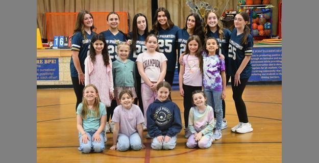 A group of cheerleaders and young girls posing together in a gym, promoting teamwork and school spirit at Blue Point Elementary.