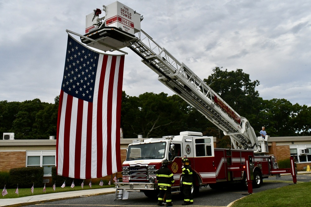 Firefighters raising American flag.