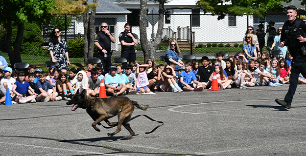 Students watching dog race police officer.