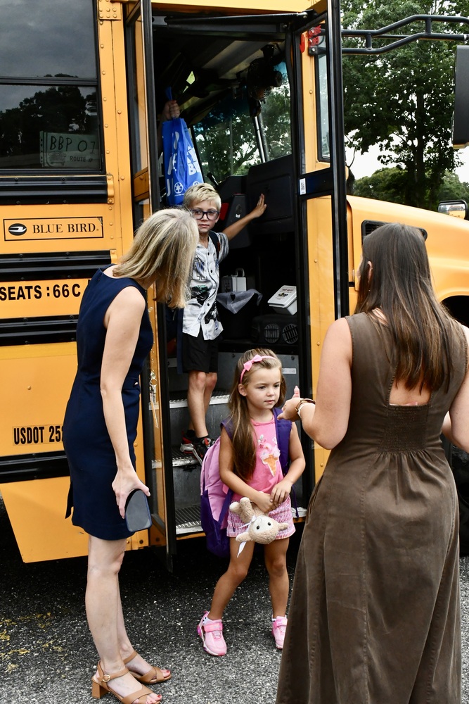 Students greeting teachers off of school bus.