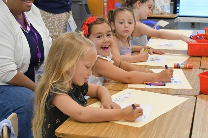 Students smiling while drawing at table.