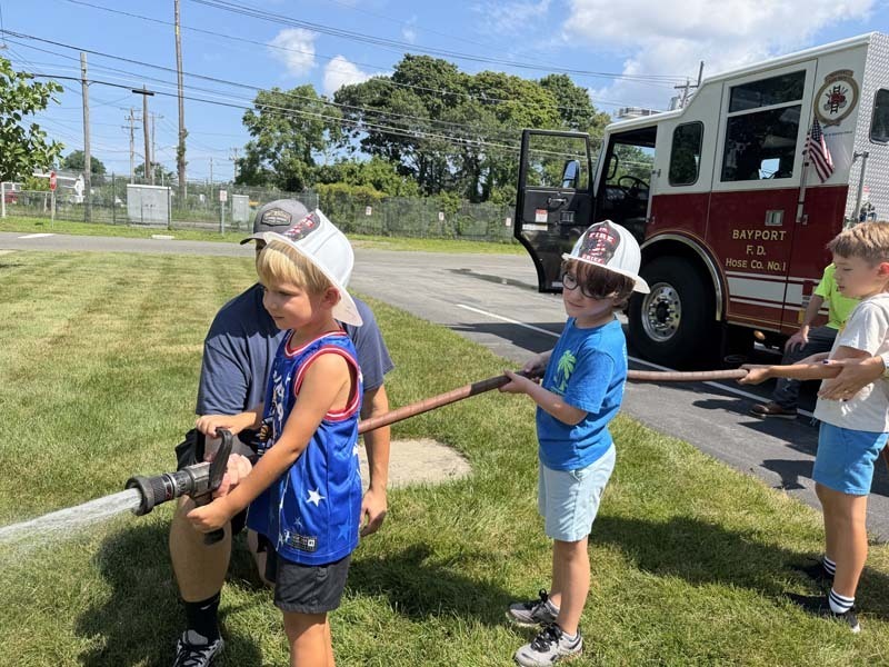 Students using fire hose outside.