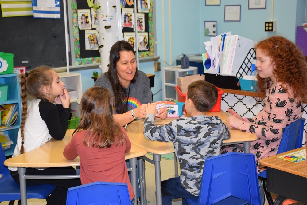 Teachers and students gathered around a table with crafts