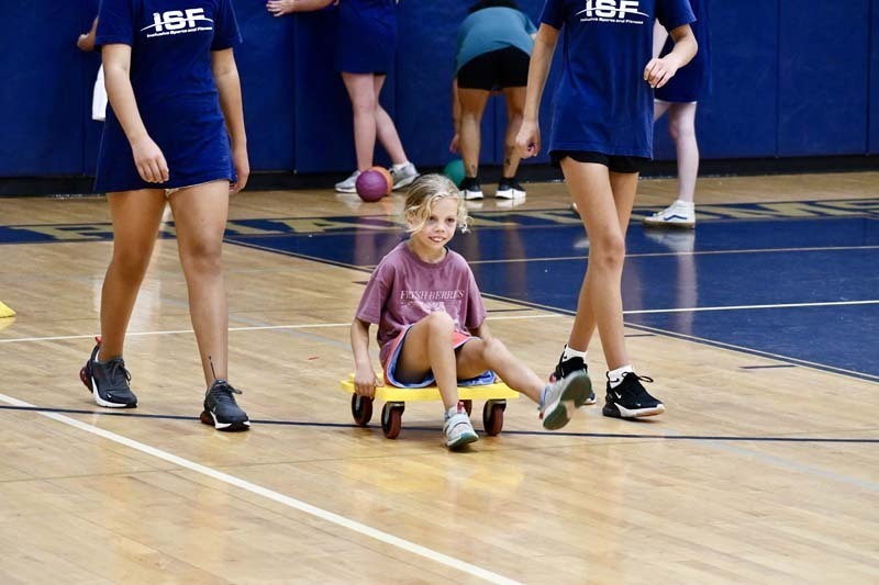 Student rolling on yellow board with wheels.