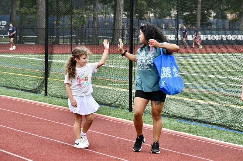 Students high fiving on track outside.