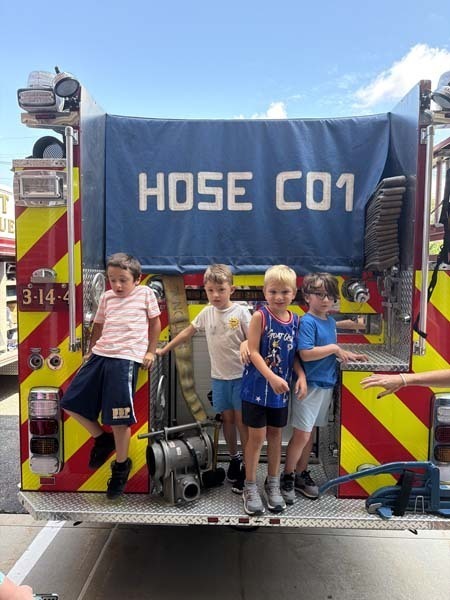 Students outside standing on fire truck.