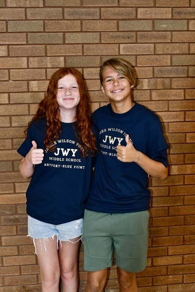 Students smiling against brick wall.