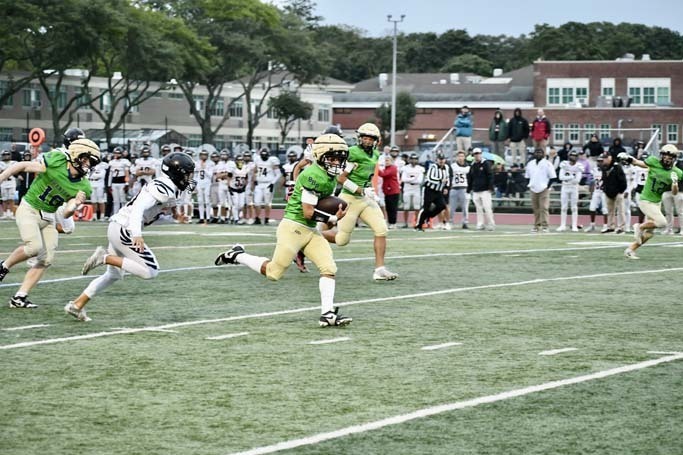 Student football players running on field.