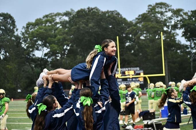 Cheerleaders lifting another girl into the air.